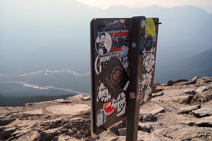 Pegatinas en la señalización de la cima del monte Ha Ling, en las Rocosas.