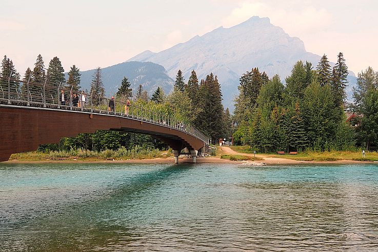 Passerelle piétonne au-dessus de la Bow River avec le mont Rundle en arrière-plan à Banff.