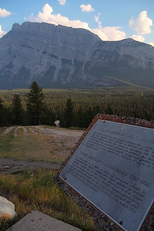 Plaque explicative sur l'histoire de Tunnel Mountain au point de vue des Hoodoos, avec le mont Rundle en arrière-plan.