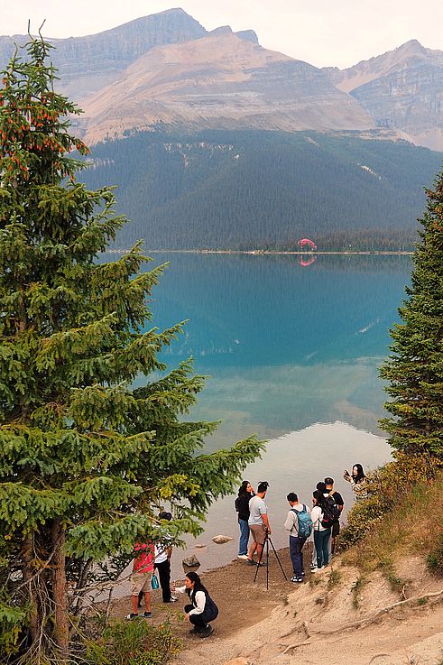 Touristes sur la rive du lac Bow avec le lodge Num-Ti-Jah en arrière-plan.