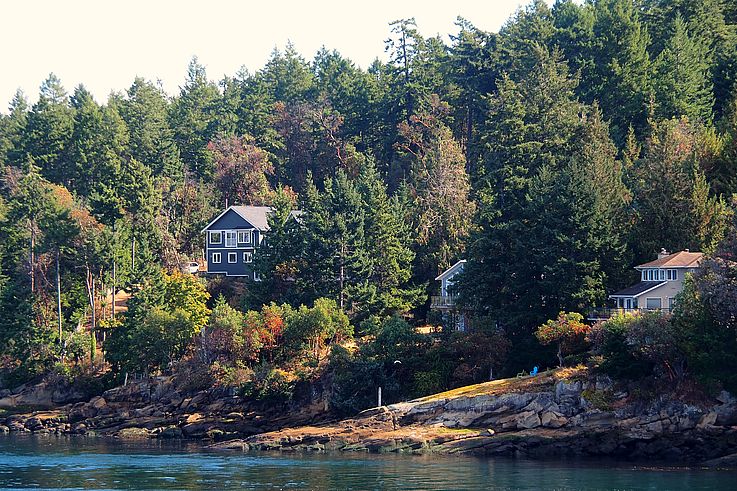 Residential houses on the wooded rocky coast of Mayne Island.