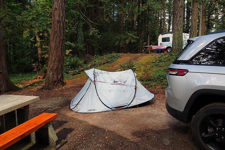 Quechua tent and SUV at a forest campsite.