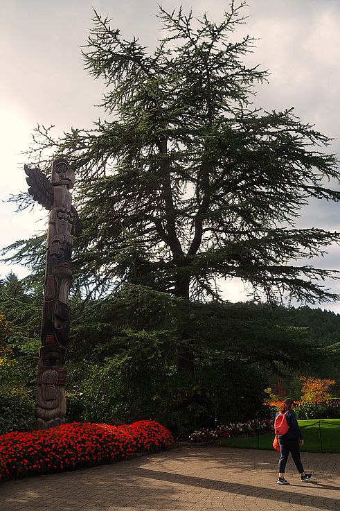 Totem pole and red flower beds at Butchart Gardens.