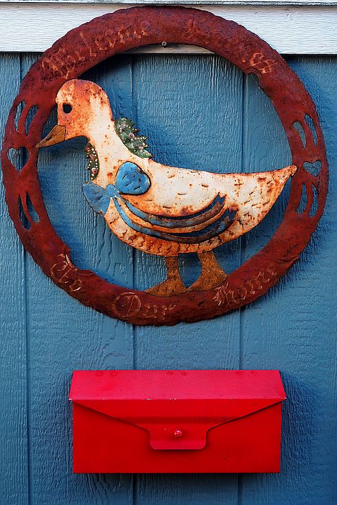 Rusty metal wall decoration depicting a bird above a red mailbox in Victoria.