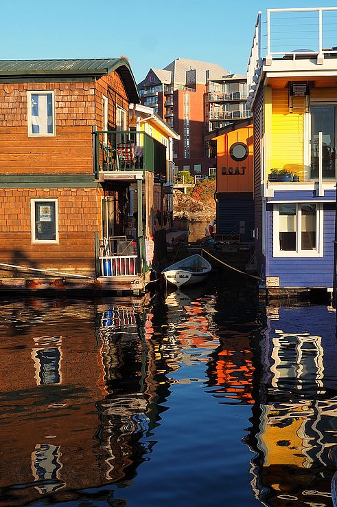 Colorful floating houses and reflections on the water at Fisherman's Wharf in Victoria.