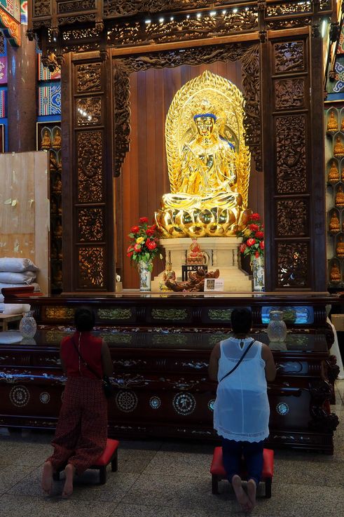 Golden Buddha and worshippers praying at Kek Lok Si Temple in George Town.