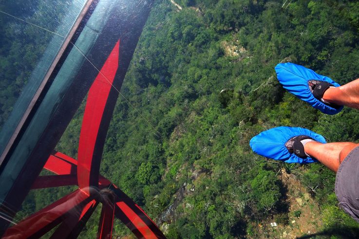 Pies en el suelo de cristal del Eagle Nest Skywalk, Langkawi Sky Bridge.