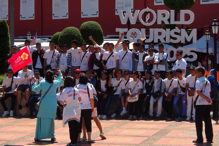 Turistas frente a Christ Church de Melaka y el cartel de World Tourism 2025.