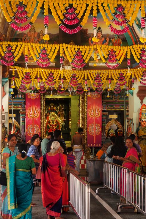 Interior del templo Sri Mariamman en Chinatown, escenas de dioses hindúes y guirnaldas florales.