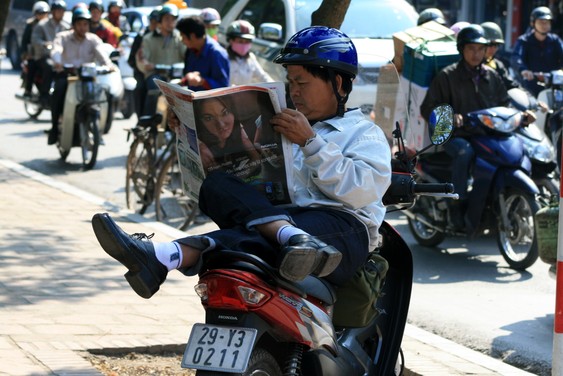 Reading on a scooter in Hanoi...